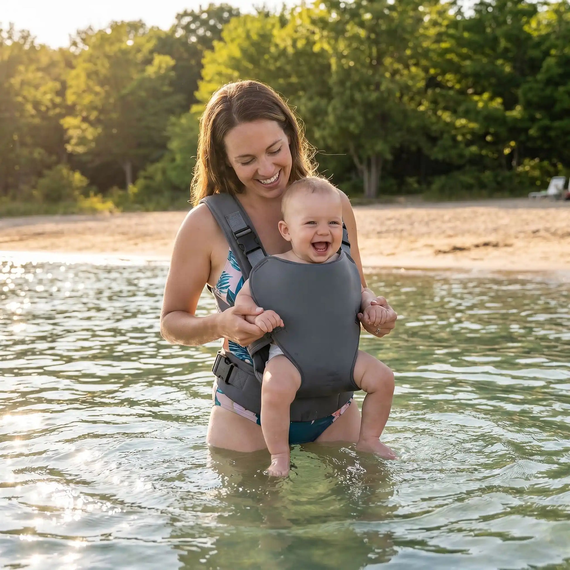 Bébé dans son porte-bébé sur maman au lac à la plage