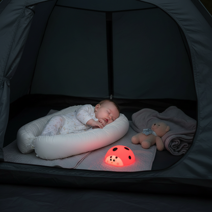 Bébé dors dans la tente dans son nid pour bébé avec sa veilleuse coccinelle allumée.